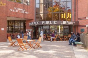 Families and children gathered outside the Norwalk Public Library, engaging in community programs, reading activities, and cultural events in a welcoming urban space.